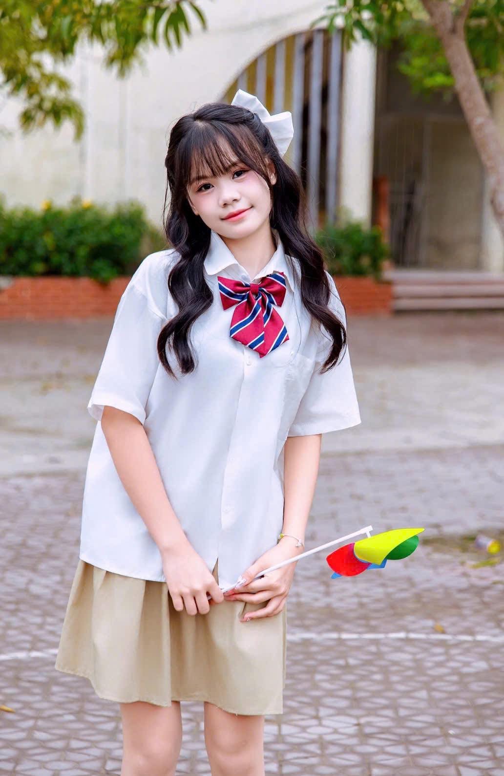 A cheerful teen girl holding a colorful pinwheel outdoors.